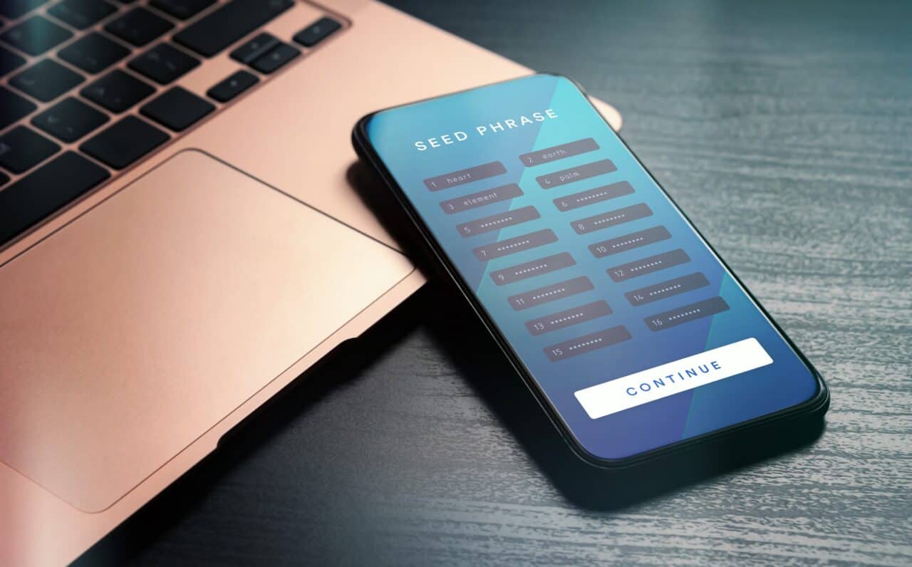 Ein Smartphone auf einem Laptop zeigt die Seed Phrase zur Wiederherstellung einer verlorenen Wallet