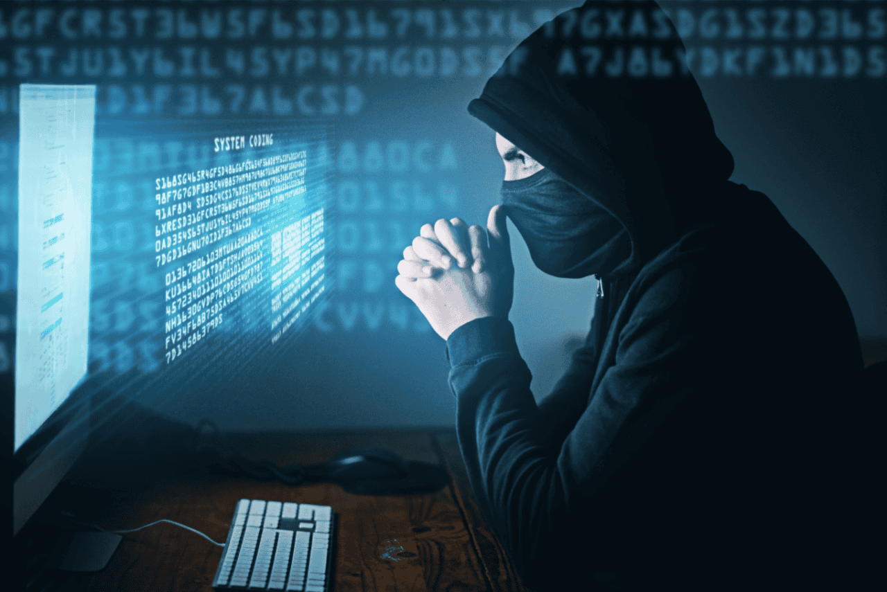 Ein maskierter Mann vor einem Computer symbolisiert Krypto-Scams.
