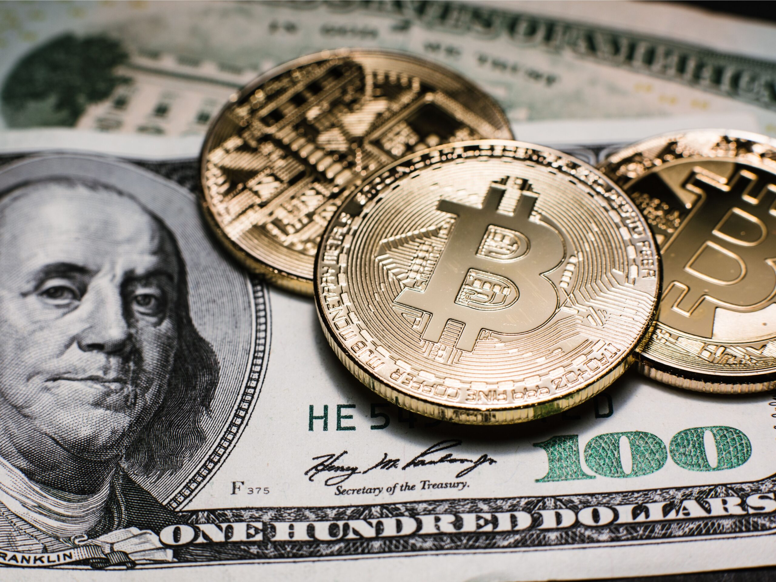 Das Bild zeigt Bitcoin-Münzen auf einem US-Dollar-Schein als Symbol für Fiatgeld vs. Krypto