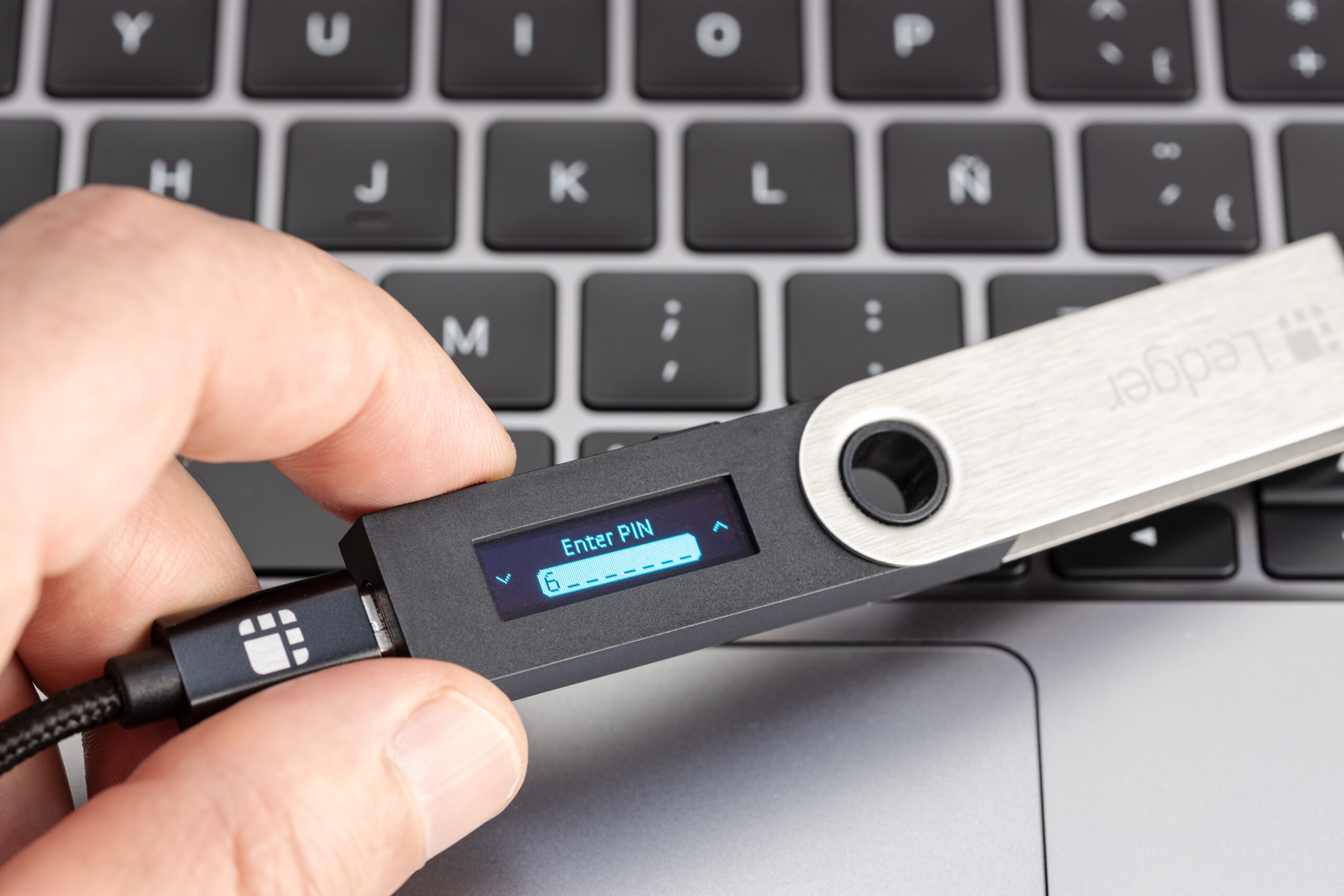 Das Bild zeigt die Einrichtung des Ledger Nano S über ein Kabel an einem Laptop.