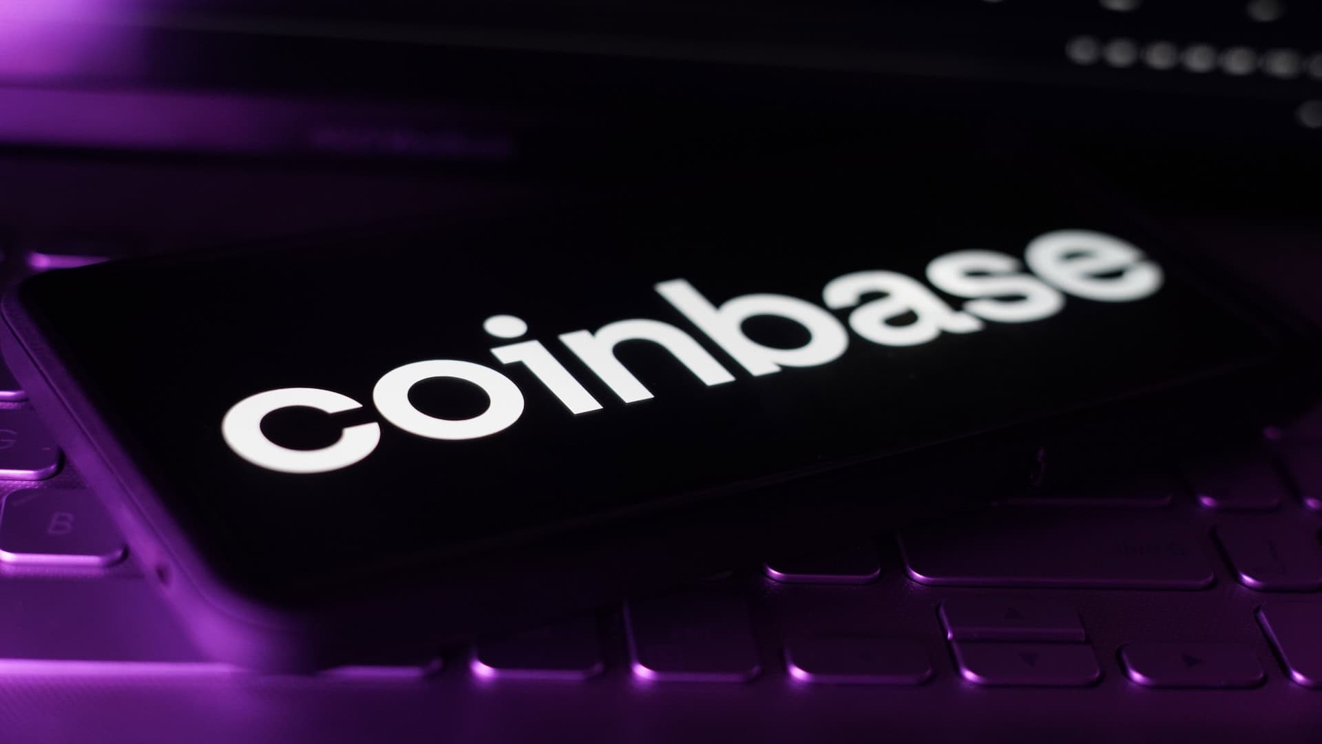 Coinbase Logo auf Smartphone mit violettem Hintergrund – Symbolbild für Coinbase Staking