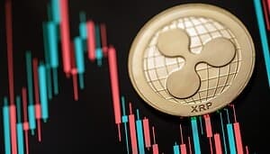 Eine Ripple (XRP)-Münze auf einem Bildschirm, der ein XRP-Kryptowährungs-Kerzenchart mit roten und grünen Balken anzeigt.