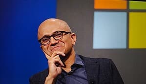 Microsoft-CEO Satya Nadella auf einer Bühne vor einem Bildschirm mit dem Microsoft Logo.