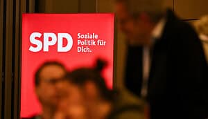 Eine unscharfe Menschengruppe unterhält sich vor dem SPD-Parteilogo.