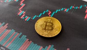 Eine Bitcoin-Münze vor einem Kerzen-Chart.
