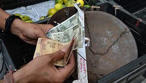 Jemand zählt indische Rupien vor einem Korb.