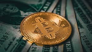 Eine vergoldete Bitcoin-Münze liegt auf verschiedenen US-Dollar-Noten.
