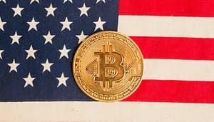 Man sieht die USA-Flagge und in der Mitte ist eine goldene Bitcoin-Münze platziert.