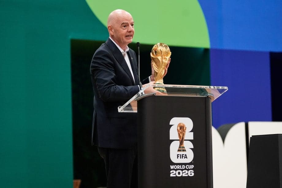 FIFA-Präsident Gianni Infantino hält den WM-Pokal vor einem Podium.