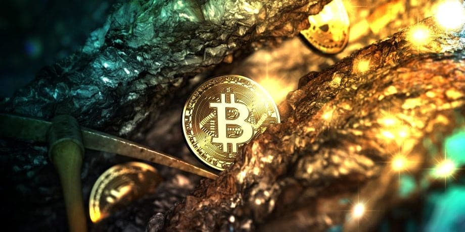 Eine Spitzhacke neben einem Bitcoin, der aus einer Goldader strahlt.