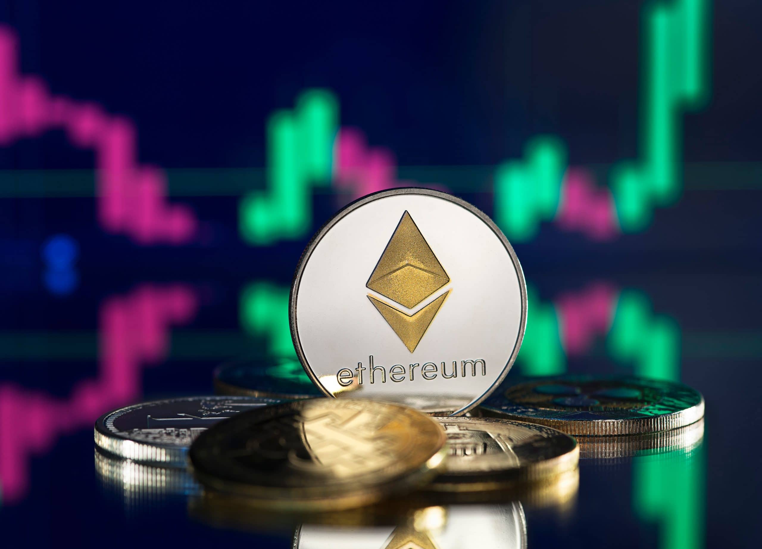 Eine physische Darstellung einer Ethereum-Münze wird zwischen anderen Münzen platziert, wobei ein digitales Finanzdiagramm mit grünen und rosafarbenen Kerzenleuchtern im unscharfen Hintergrund die Präsenz von Ethereum auf dem Kryptomarkt hervorhebt.