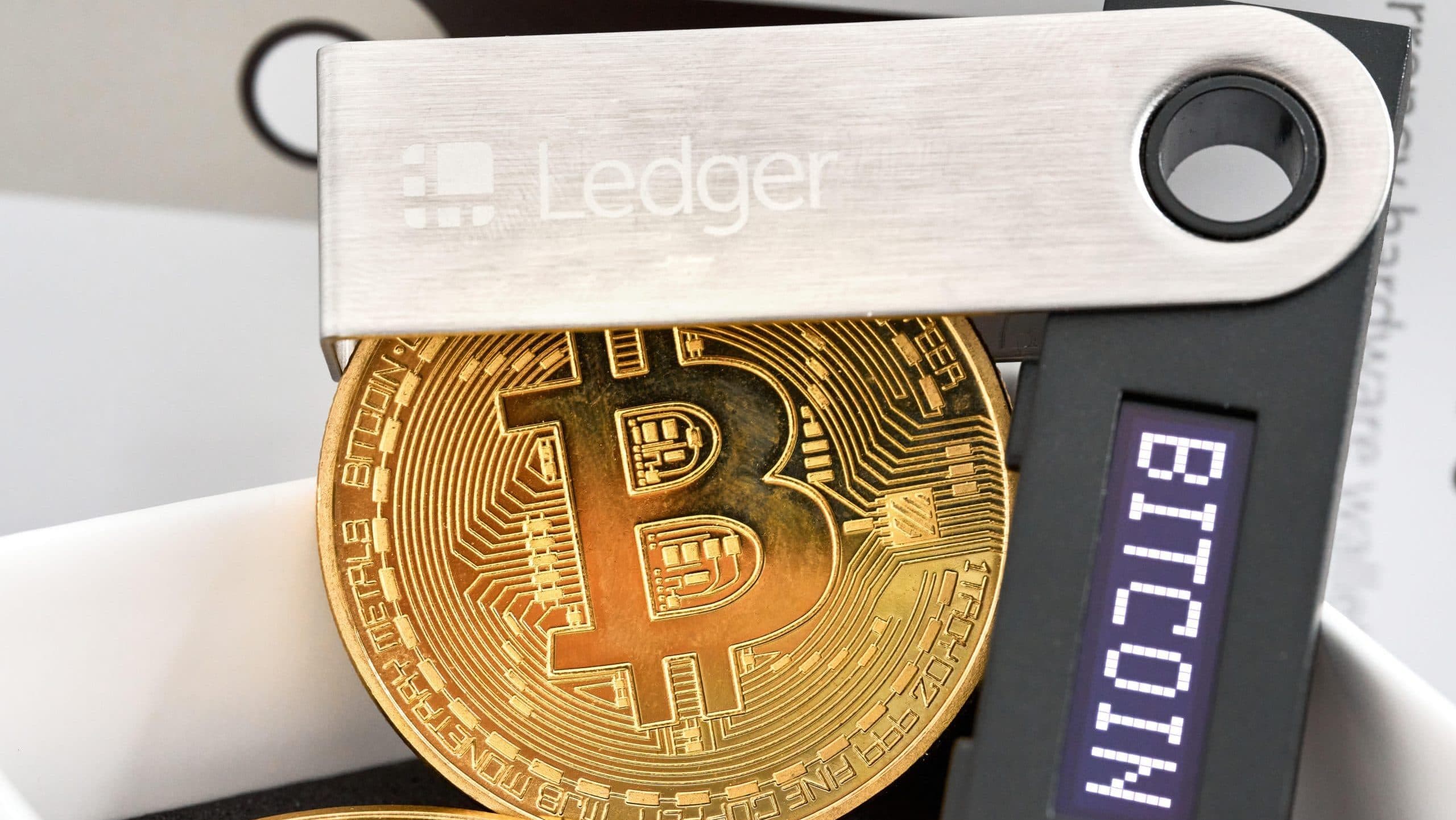 Das Bild zeigt eine Ledger Wallet und eine Bitcoin-Münze