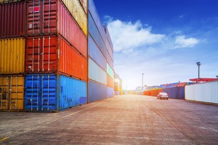 Empty road and containers in harbor at sunset