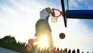 Street basketball player performing power slum dunk.