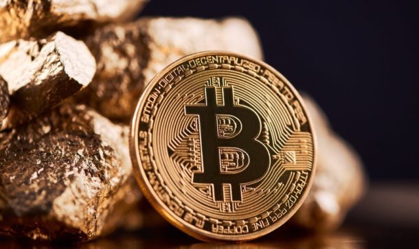 Bitcoin-Münze lehnt an Goldstücken.