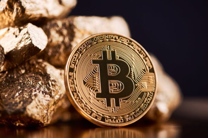 Bitcoin-Münze lehnt an Goldstücken.