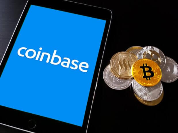 Smartphone mit Coinbase Logo udn Bitcoin-Münzen