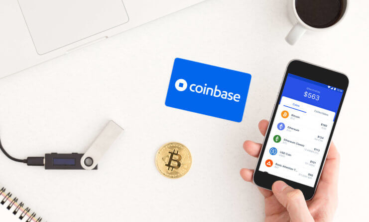 Man sieht ein Smartphone mit der Coinbase App, eine Bitcoin-Münze sowie ein HArdware Wallet auf einem Tisch liegen.