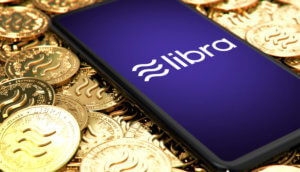 Libra-Logo auf Smartphone, das auf Goldmünzen mit Libra-Logo liegt