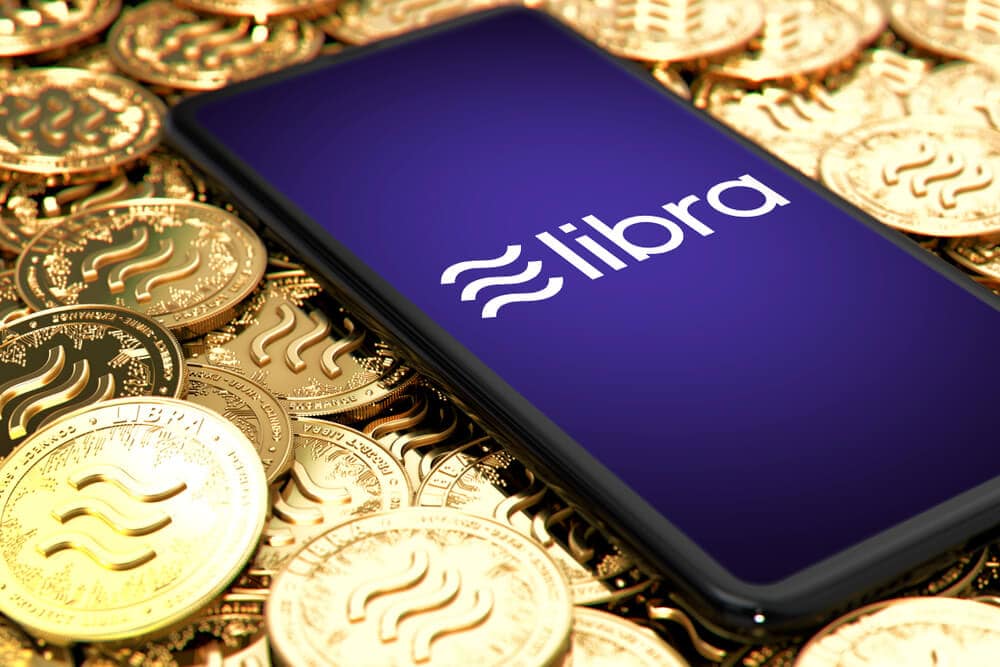 Libra-Logo auf Smartphone, das auf Goldmünzen mit Libra-Logo liegt