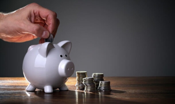 BoostVC schließt 40 Millionen US-Dollar Fundingrunde Ein weißes Sparschwein steht auf einem Tisch und eine Münze wird eingeworfen.