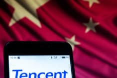 Smartphone mit Schriftzug Tencent vor chinesischer Flagge.