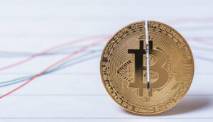 Eingeschnittene Bitcoin-Münze vor stilisiertem Chart
