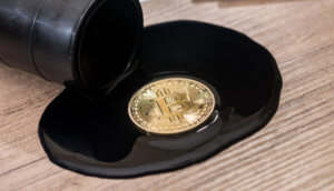 Eine Bitcoin-Münze liegt auf einem Tropfen Öl auf einem Holztisch