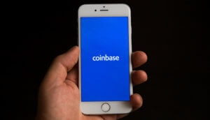 hand hält ein smartphone, auf dem das coinbase-logo zu sehen ist
