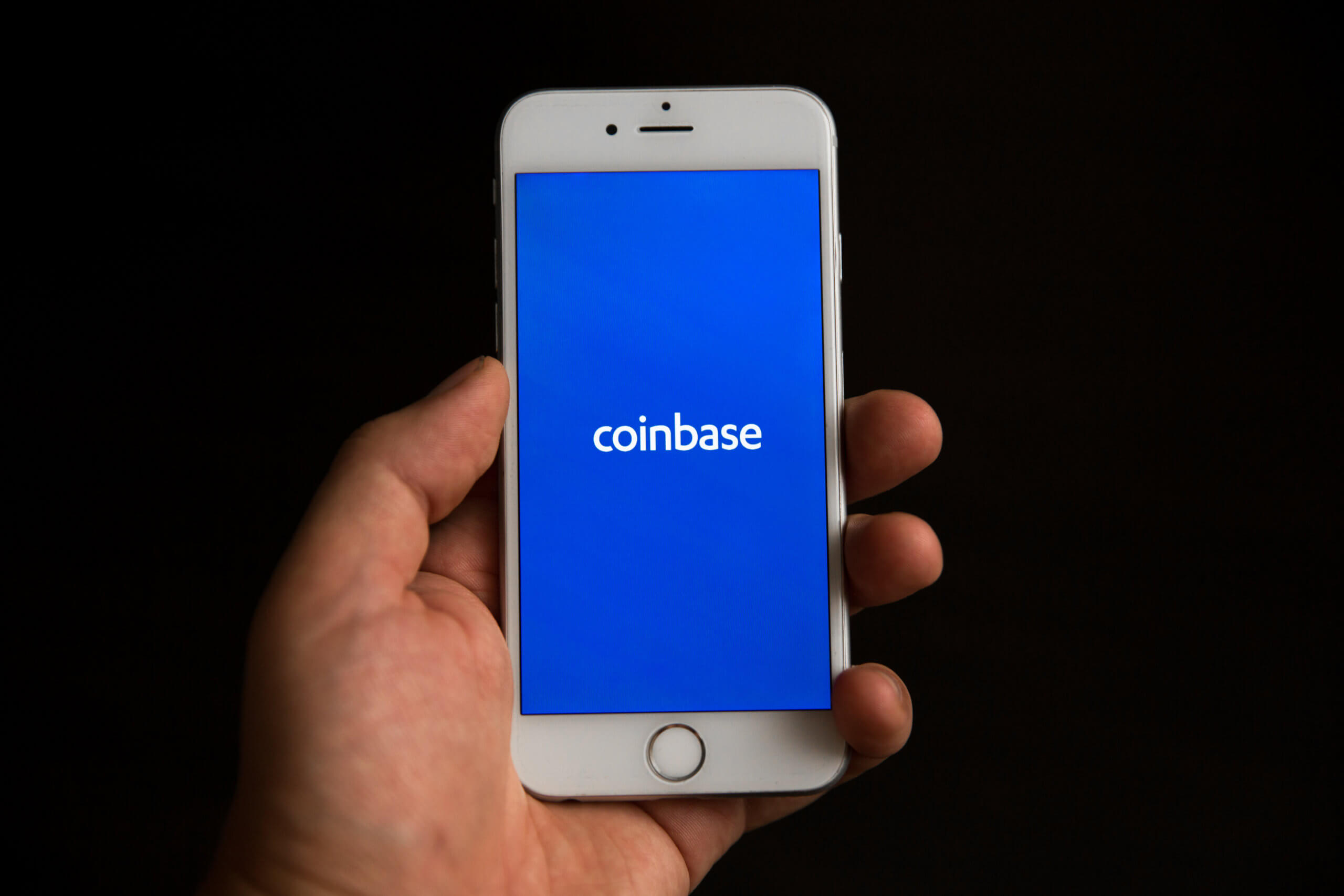 hand hält ein smartphone, auf dem das coinbase-logo zu sehen ist