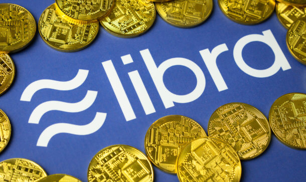 Libra könnte „die globale Zahlungsindustrie umgestalten“ Libra-Münzen liegen auf einem blauen Hintergrund, der das Logo von Libra zeigt.