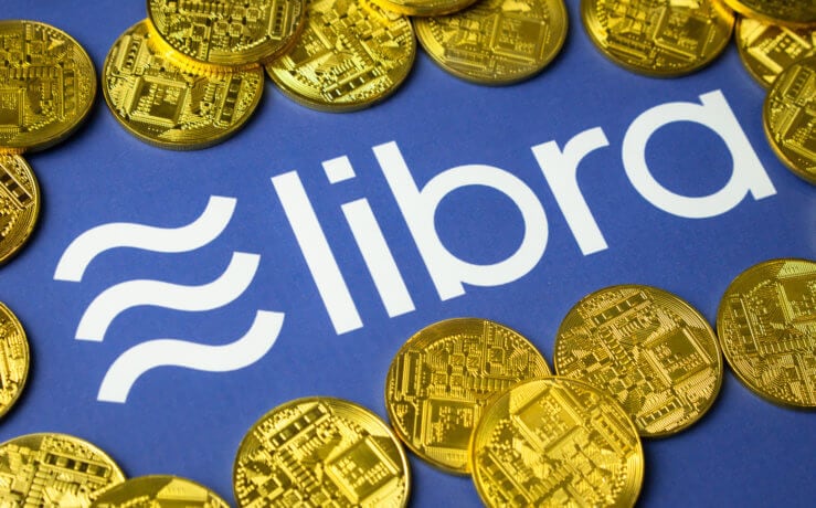 Libra-Münzen liegen auf einem blauen Hintergrund, der das Logo von Libra zeigt.