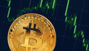bitcoin-münze vor einer chart mit grünen kerzen