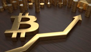 goldenes bitcoin b mit goldenem chartpfeil in plastischer darstellung weiter hinten im bild gestapelte goldene münzen auf einem braunen untergrund ansicht von schräg oben