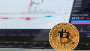 Eine stehende Bitcoin-Münze vor einer Analyse.