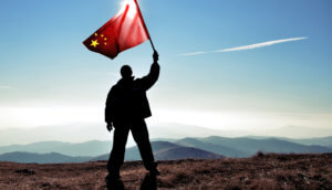 Mann steht auf Berg und hält chinesische Flagge hoch als Zeichen für den Start von CBDC
