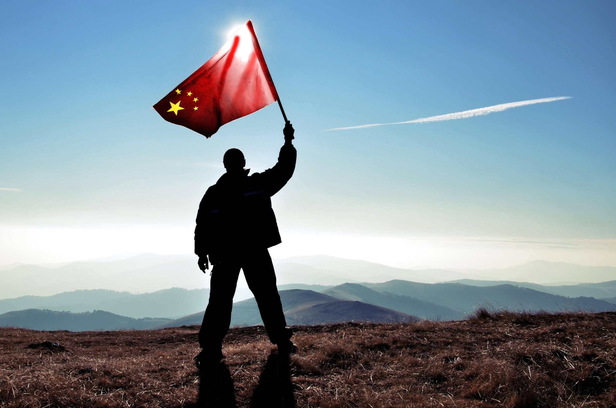 Mann steht auf Berg und hält chinesische Flagge hoch als Zeichen für den Start von CBDC