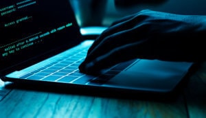 Hacker sitzt vor einem Laptop und tippt