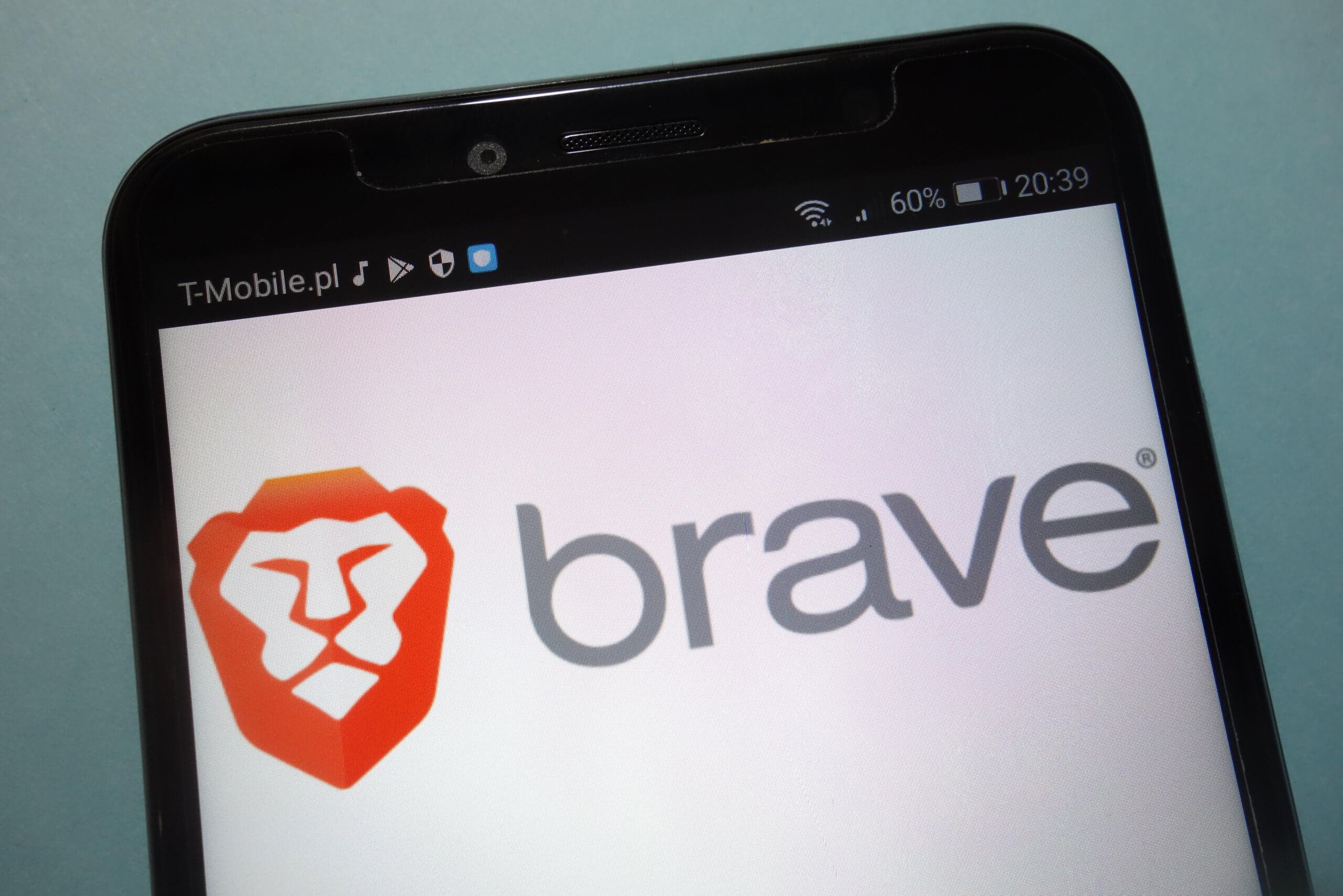 Ein Smartphone Display und im Hintergrund wird der Brave Browser angezeigt