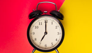 Ein Wecker der auf punkt sieben Uhr das Hintergrundbild ist zweigeteilt eine Seite ist rot und die andere Seite ist gelb