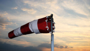 Windsack in den Farben Rot und Weiß dreht sich zum Wind im Hintergrund geht die Sonne unter