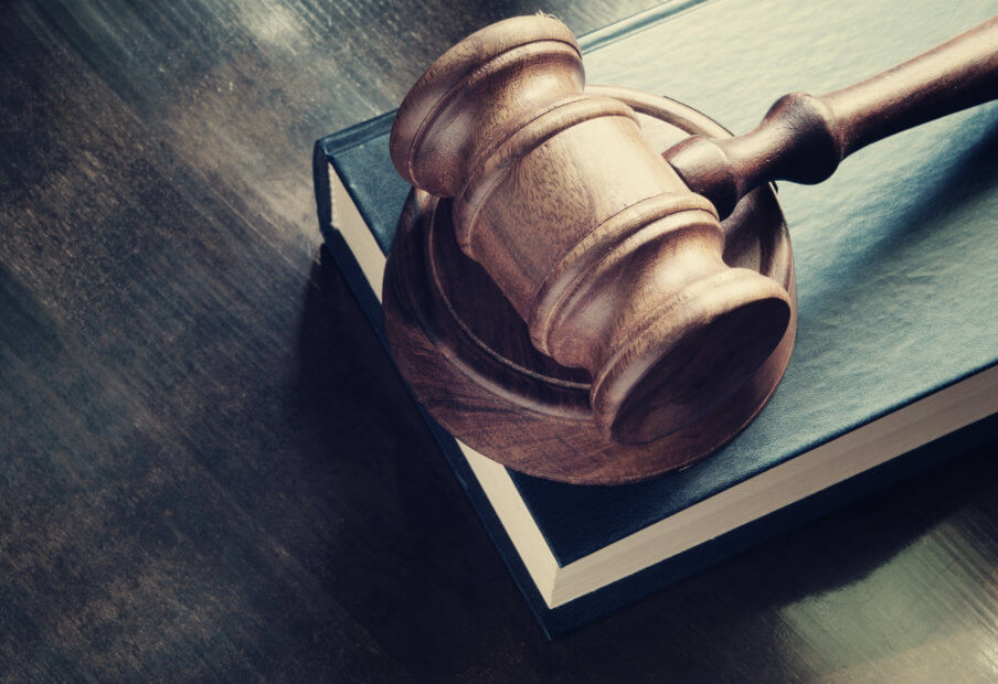 Kik versus SEC: Entscheidung bahnt sich an ein hammer liegt auf einem schwarzen buch auf einem holztish