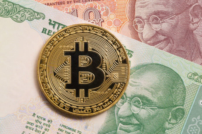 Goldene Bitcoin Münze liegt auf indischen Geldscheinen