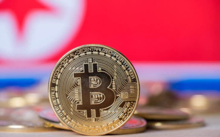 Eine balancierende Bitcoin-Münze vor einer Nordkorea-Flagge