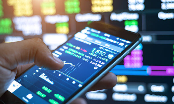 Blockchain-Assets: USA bekommen neues Trading-Netzwerk smartphone mit daumen zeigt charts im hintergrund börse