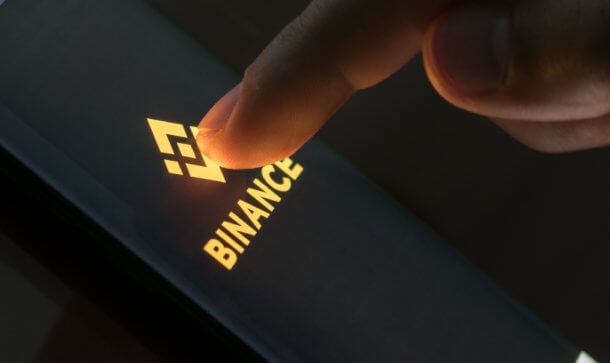 Bitcoin-Börse: Hat die Konkurrenz DDos-Attacken auf Binance gestartet? finger drückt auf smartphone mit binance-logo