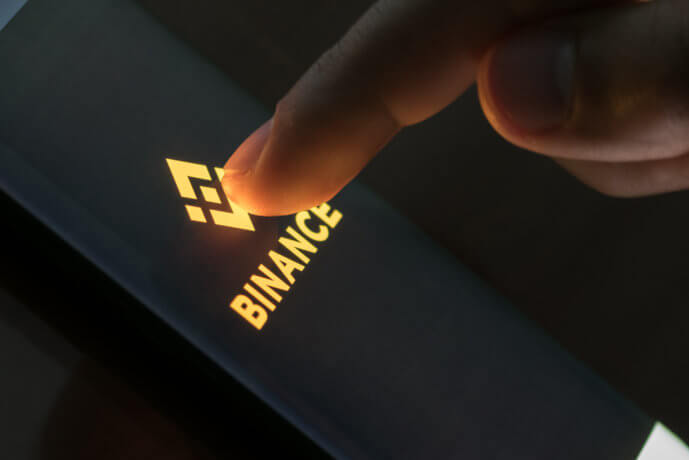 finger drückt auf smartphone mit binance-logo