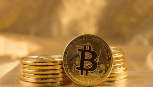 bitcoin-münze steht vor zwei stapeln mit bitcoin-münzen vor einem goldenen hintergrund