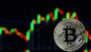 bitcoin-münze-steht-vor-einer-chart-mit-grünen-und-roten-kerzen