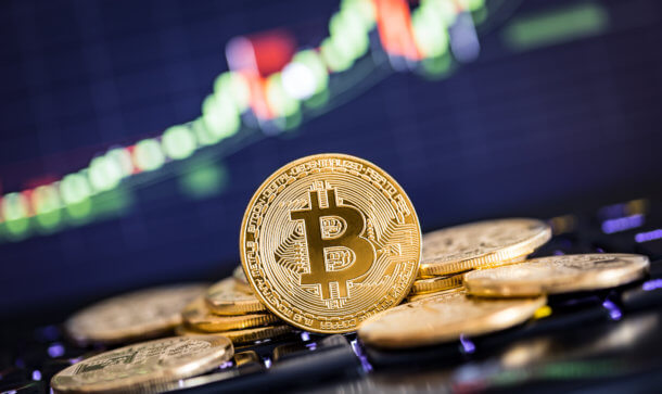bitcoin-münze steht vor liegenden bitcoin-münzen vor einer chart